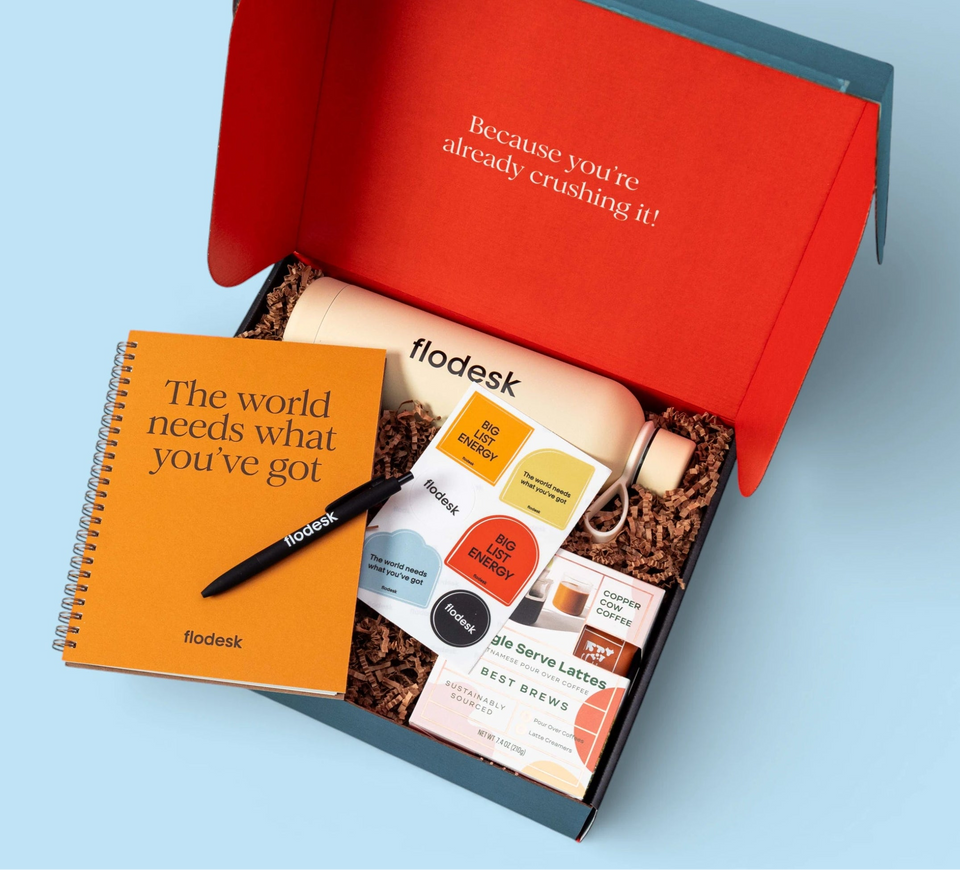 Open red gift box with a notebook and other items on a light blue background