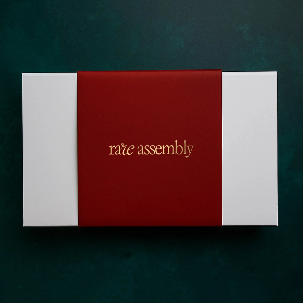 Luxe, elevated packaging by Rare Assembly featuring a soft-touch maroon band and gold-foil embossed logo by Rare Assembly.