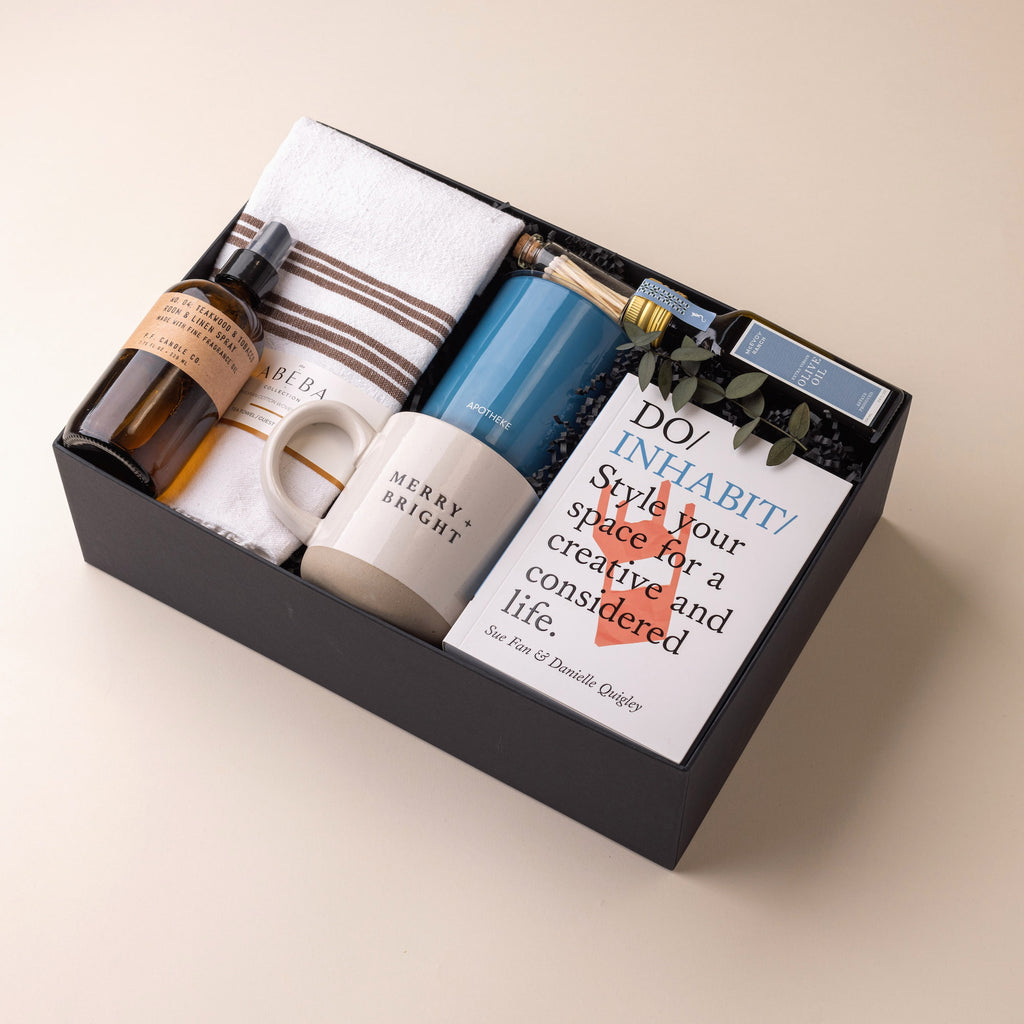 Sophisticated housewarming gift box with stoneware mug, room & linen spray, tea towel, olive oil, design book, Apotheke candle, and apothecary matches.