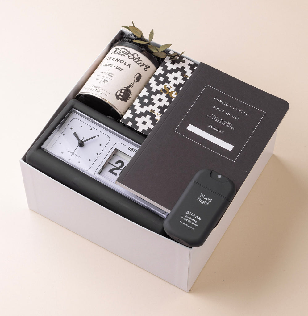 Modern gift box with retro calendar clock, notebook, chocolate, hand sanitizer and granola.